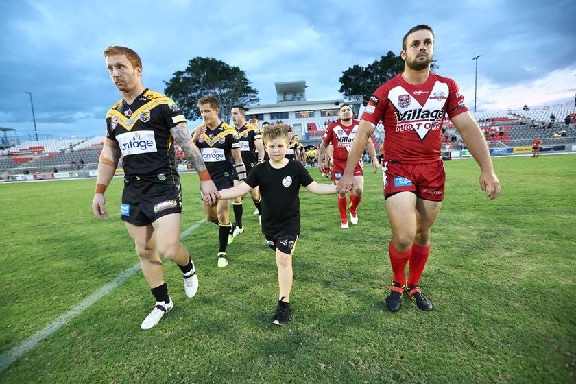 Olliver Ackerman walks onto the field, holding the hands of both captains. Photo: QRL Media